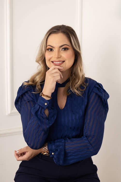 Advogada Yasmine Barbosa Alves de blusa azul-marinho, sentada e sorrindo