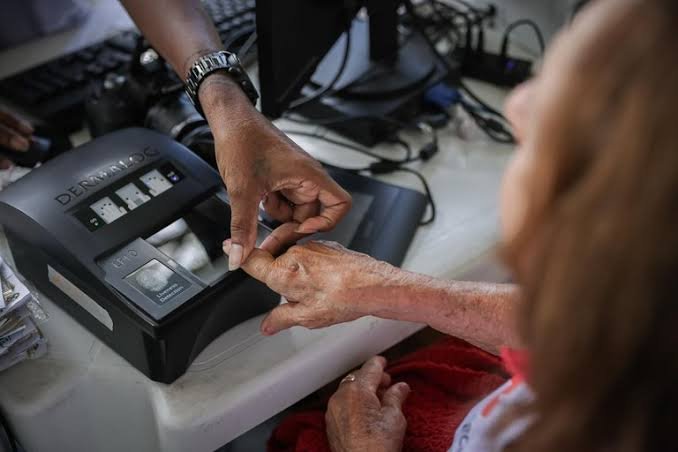 Idosa cadastrando a digital em um leitor biométrico